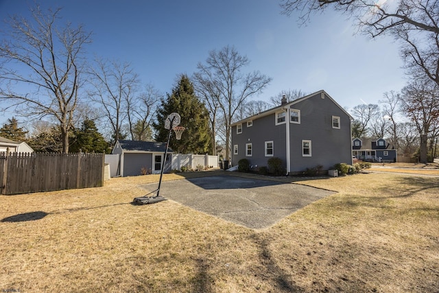 exterior space with an outbuilding, fence, a chimney, and a lawn