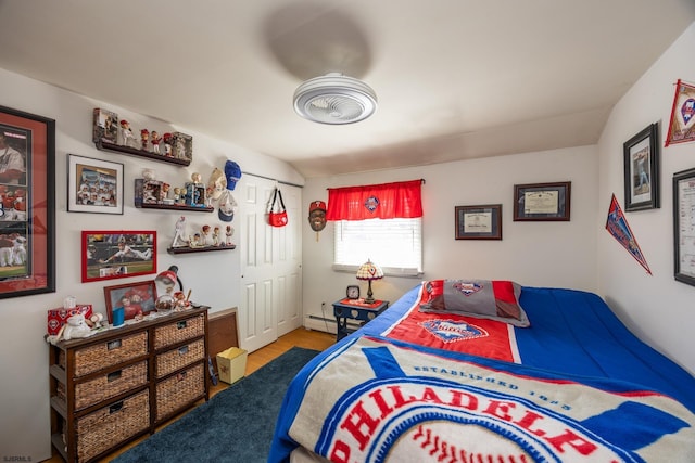 bedroom featuring a baseboard radiator, a closet, and wood finished floors