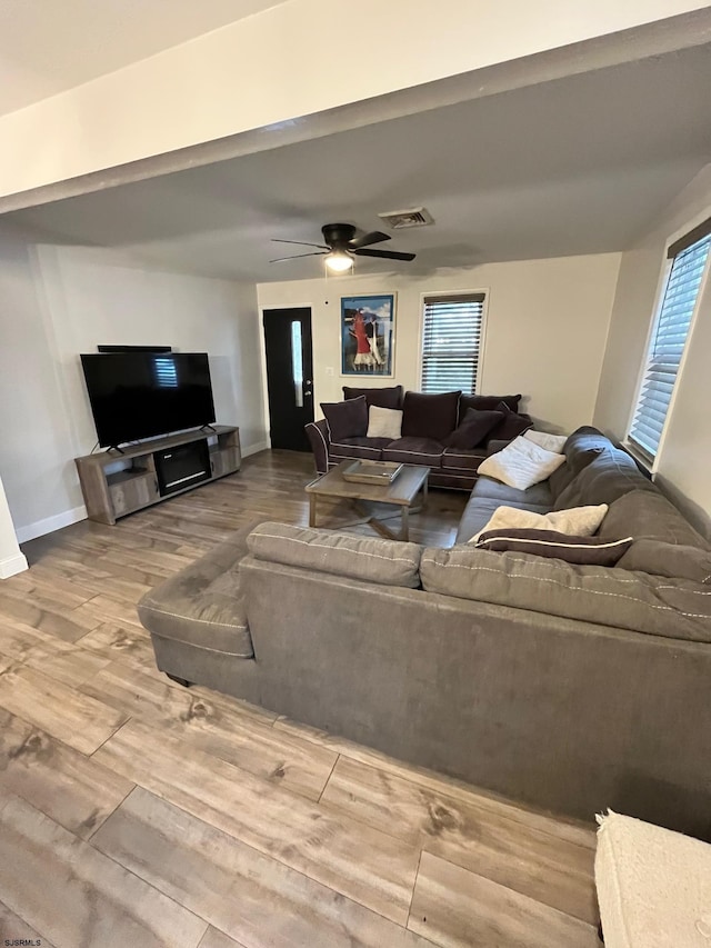 living area featuring a ceiling fan, baseboards, visible vents, and wood finished floors