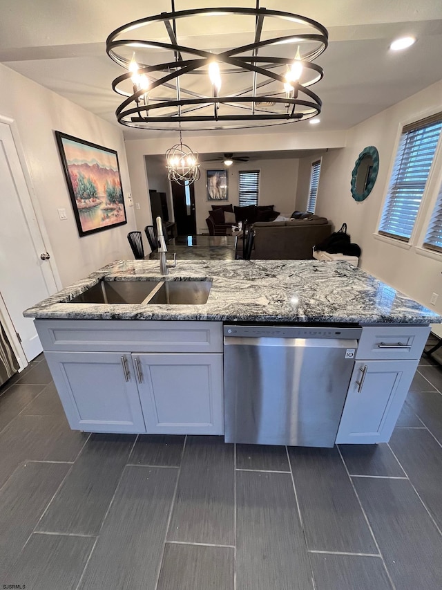 kitchen featuring light stone counters, hanging light fixtures, stainless steel dishwasher, an inviting chandelier, and a sink