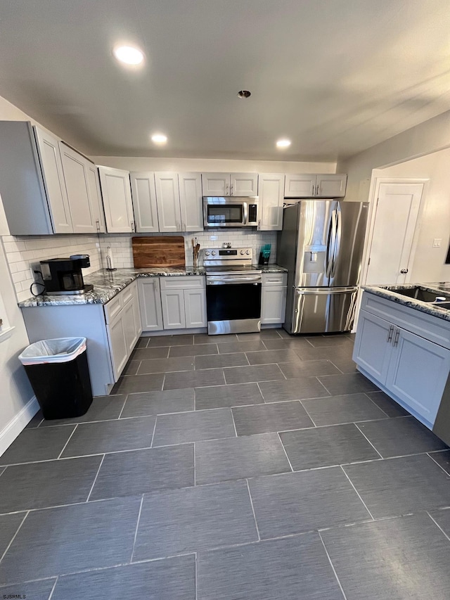 kitchen featuring light stone counters, recessed lighting, stainless steel appliances, a sink, and tasteful backsplash