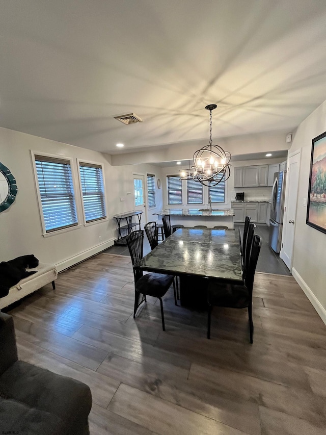 dining area with a chandelier, dark wood-style flooring, visible vents, and baseboards