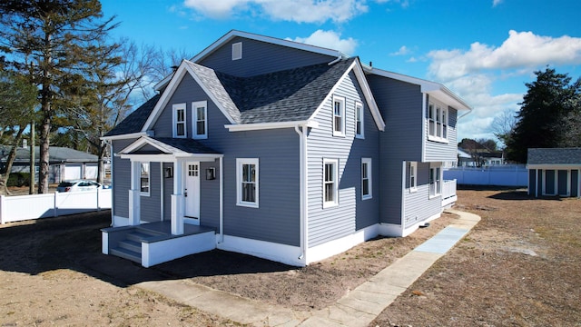 view of front facade with a shingled roof and fence