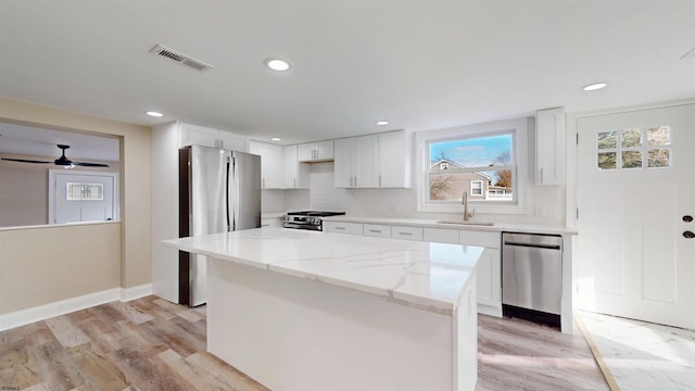 kitchen featuring light stone counters, visible vents, backsplash, appliances with stainless steel finishes, and a sink