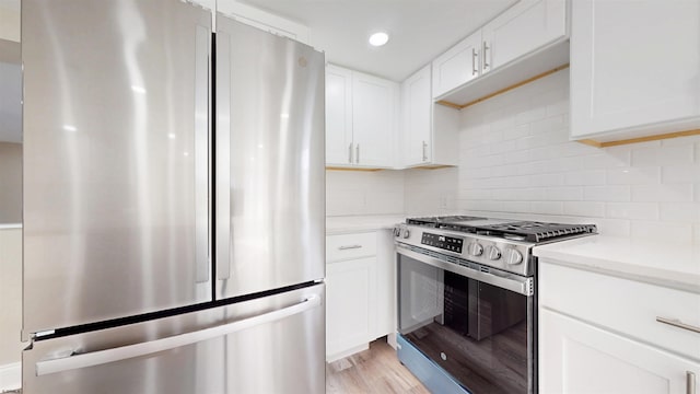 kitchen with appliances with stainless steel finishes, light wood-type flooring, white cabinetry, backsplash, and recessed lighting