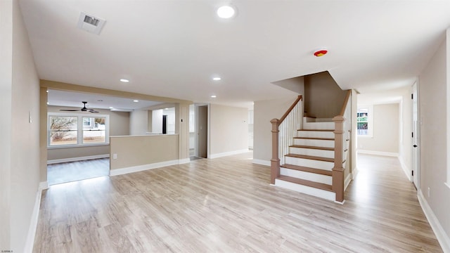 unfurnished living room with stairway, baseboards, visible vents, and light wood-style floors