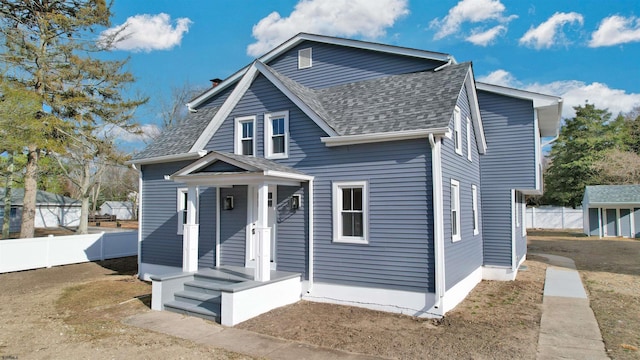 bungalow featuring fence and roof with shingles