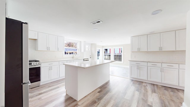 kitchen featuring light wood finished floors, visible vents, stainless steel appliances, light countertops, and white cabinetry