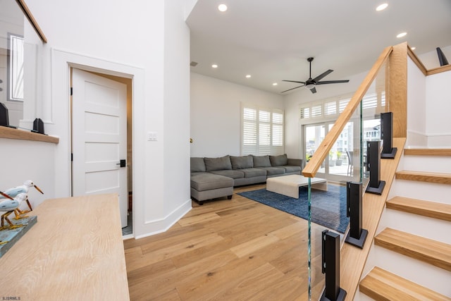 living area with recessed lighting, ceiling fan, light wood-type flooring, baseboards, and stairs