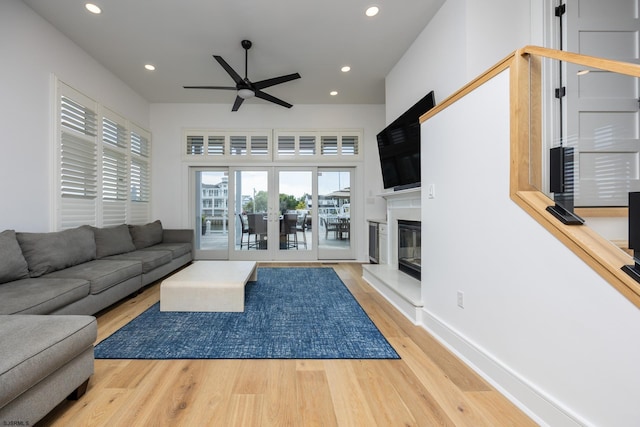 living area featuring recessed lighting, baseboards, wood finished floors, and a glass covered fireplace