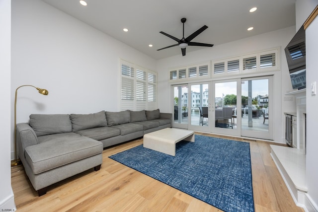 living area featuring ceiling fan, a high ceiling, recessed lighting, and light wood-style floors