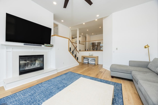 living room with ceiling fan, recessed lighting, wood finished floors, stairs, and a glass covered fireplace