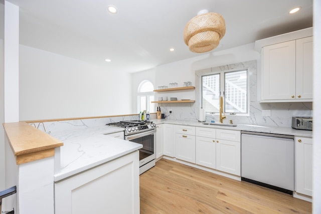 kitchen with gas range, tasteful backsplash, white dishwasher, and light wood-style flooring