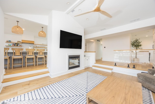 living room with lofted ceiling, wood finished floors, a glass covered fireplace, and visible vents