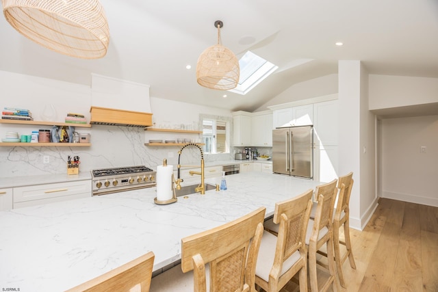 kitchen with premium appliances, open shelves, tasteful backsplash, white cabinets, and vaulted ceiling with skylight