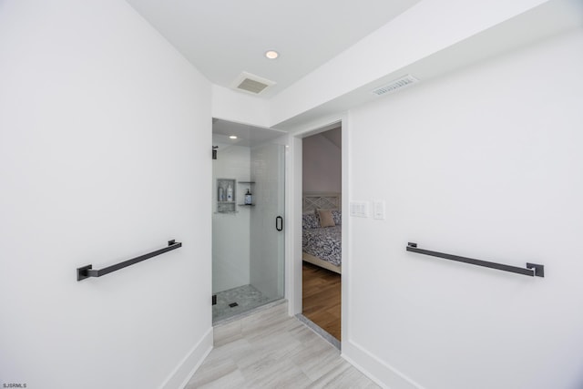 full bath with a stall shower, wood finished floors, visible vents, and baseboards