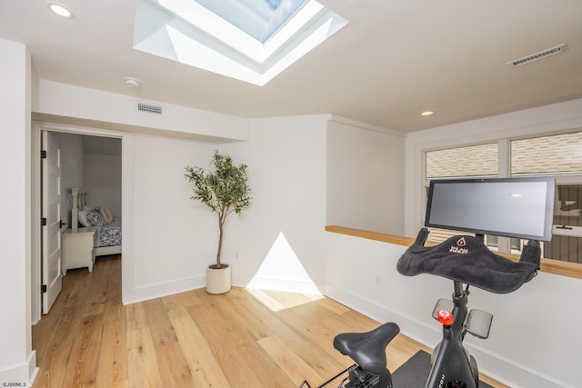 workout area with a skylight, visible vents, wood finished floors, and recessed lighting