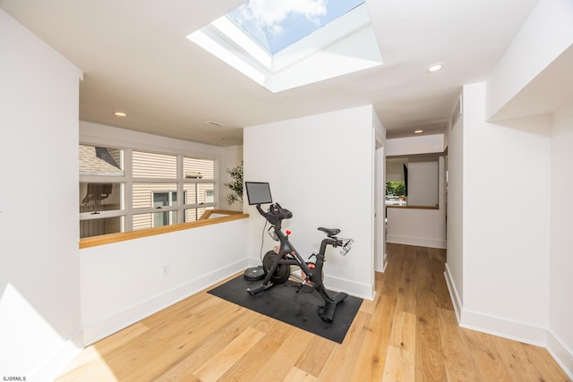 workout room featuring a skylight, baseboards, wood finished floors, and recessed lighting