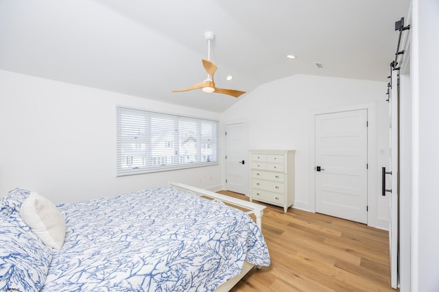 bedroom with lofted ceiling, recessed lighting, visible vents, light wood-style flooring, and a barn door