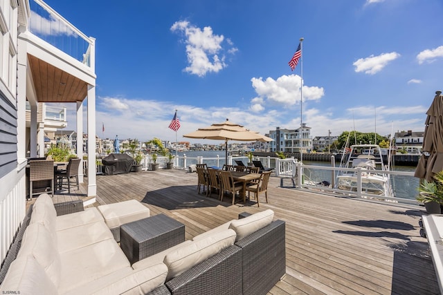 wooden terrace with outdoor dining area, a water view, a grill, and an outdoor living space