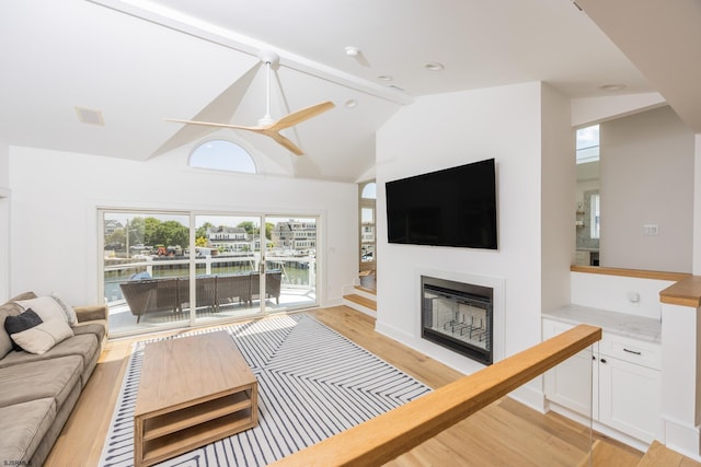 living room with a fireplace, visible vents, light wood-style flooring, a ceiling fan, and vaulted ceiling