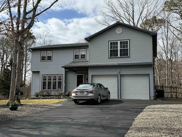 traditional-style house with a garage, driveway, fence, and central AC unit