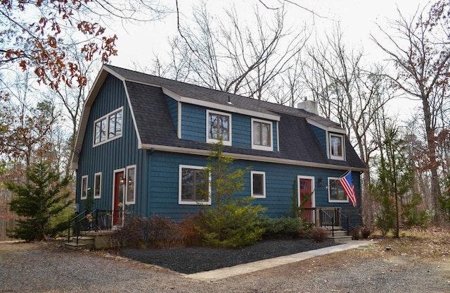 dutch colonial featuring roof with shingles, a chimney, and a gambrel roof