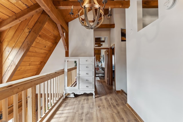 hall with baseboards, lofted ceiling with beams, wood ceiling, wood finished floors, and a chandelier