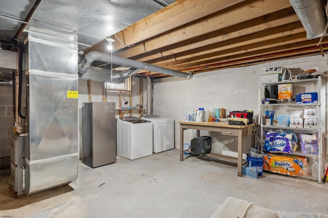 unfinished below grade area with washer and dryer, freestanding refrigerator, and heating unit