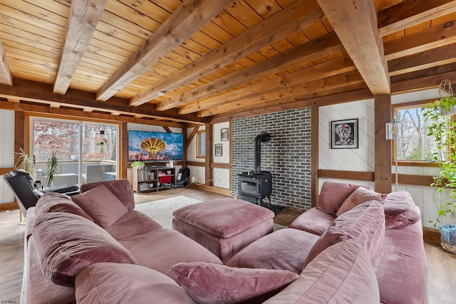 living room with a wood stove, wooden ceiling, beam ceiling, and wood finished floors