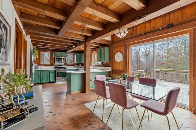 dining room featuring wood ceiling, beam ceiling, light tile patterned flooring, and wood walls