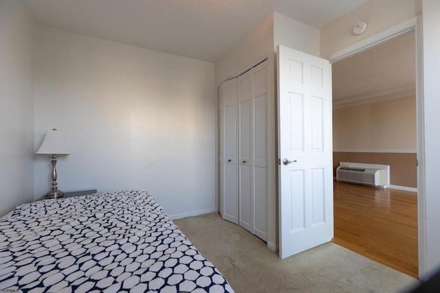 bedroom featuring light colored carpet, a closet, a wall unit AC, and baseboards