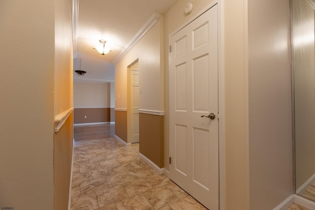 corridor with baseboards, stone finish floor, and crown molding