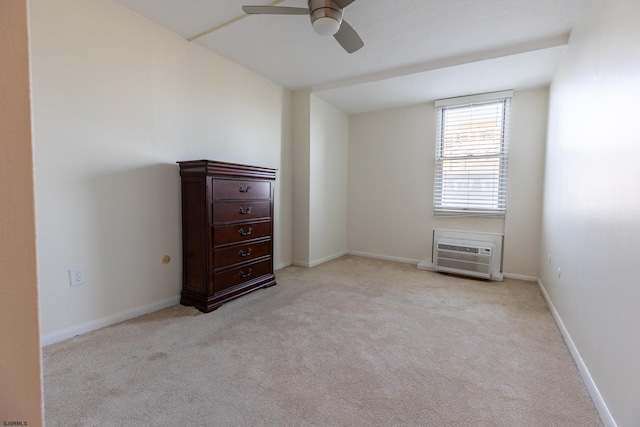 unfurnished bedroom featuring an AC wall unit, light colored carpet, ceiling fan, and baseboards