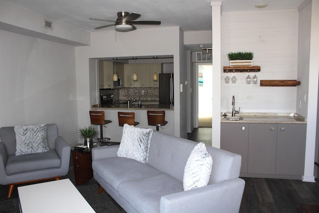 living room featuring ceiling fan, dark wood-style flooring, indoor wet bar, and visible vents