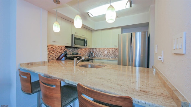 kitchen with a peninsula, tasteful backsplash, appliances with stainless steel finishes, and a sink