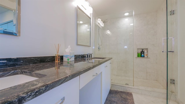 bathroom with double vanity, a shower stall, a sink, and tile patterned floors