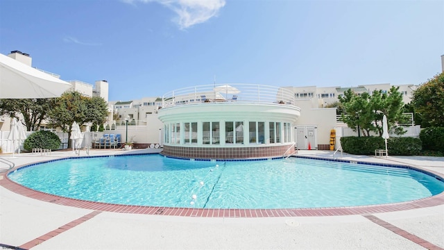 community pool with a patio area and fence