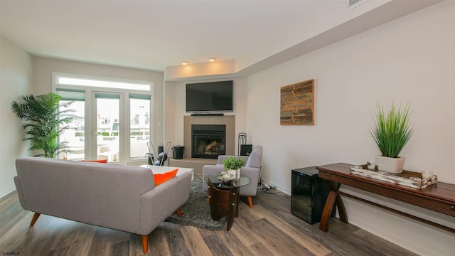 living area with a fireplace with raised hearth, wood finished floors, and baseboards