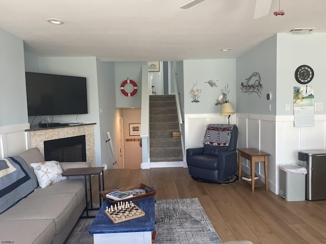 living room with a wainscoted wall, stairway, a fireplace, and wood finished floors