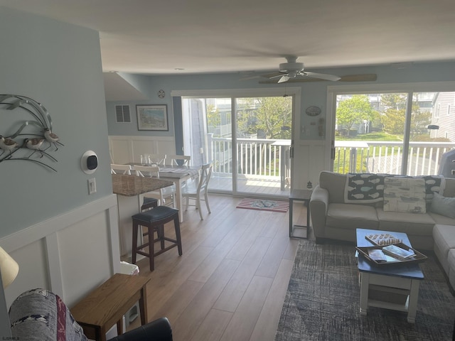 living room with wainscoting, wood finished floors, and a decorative wall