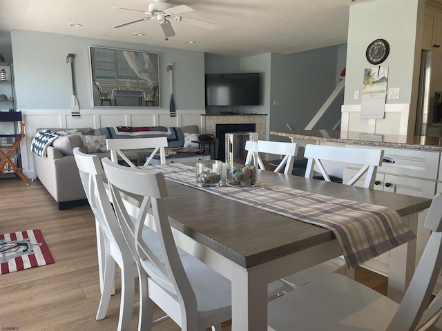 dining room featuring a ceiling fan, recessed lighting, a fireplace, and light wood finished floors