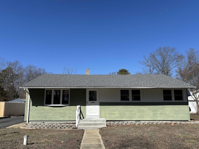 view of front of home featuring a shingled roof, a chimney, and fence