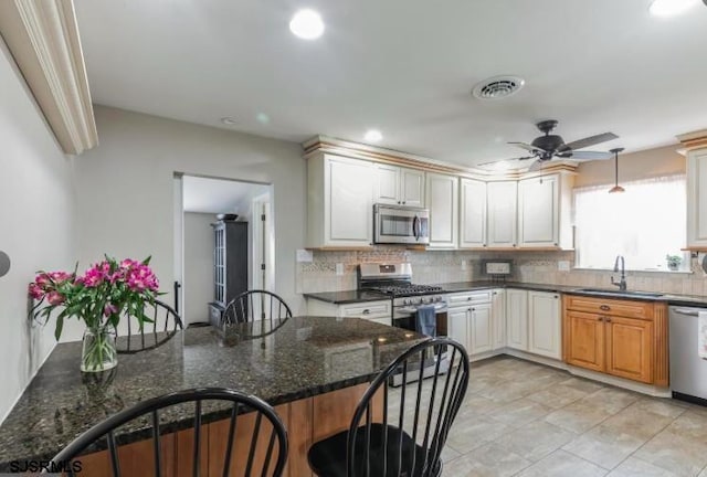 kitchen featuring stainless steel appliances, tasteful backsplash, a sink, and a ceiling fan