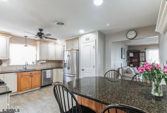 kitchen with decorative backsplash, appliances with stainless steel finishes, a breakfast bar, and a sink