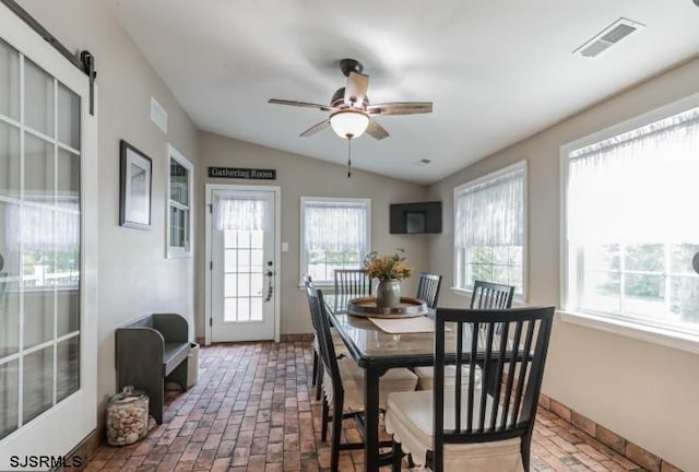 dining room with vaulted ceiling, brick floor, visible vents, and a ceiling fan