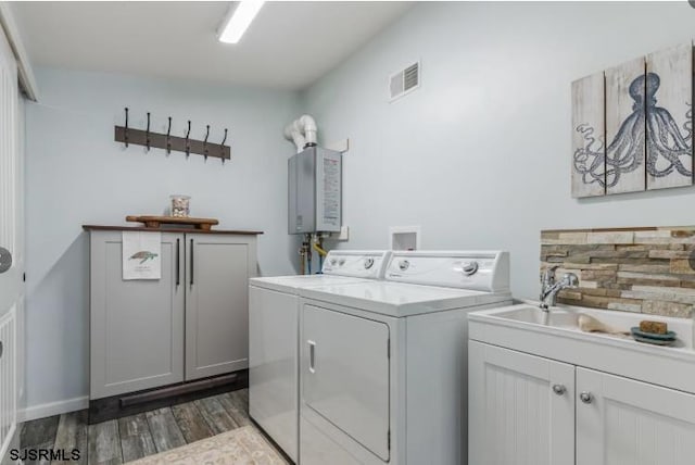 laundry area with dark wood-style flooring, washer and clothes dryer, visible vents, cabinet space, and a sink