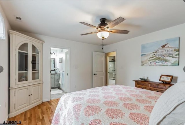 bedroom featuring ceiling fan, ensuite bath, visible vents, and light wood-style floors