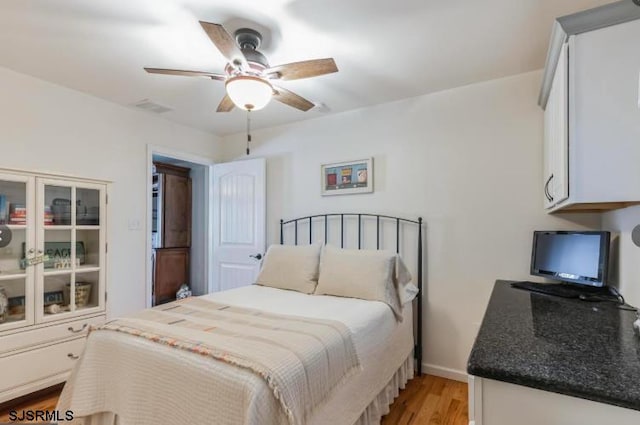 bedroom featuring light wood finished floors, ceiling fan, visible vents, and baseboards