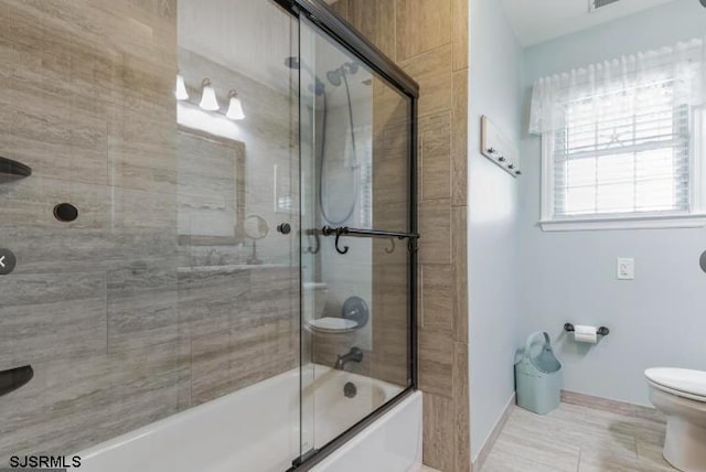 bathroom with combined bath / shower with glass door and toilet